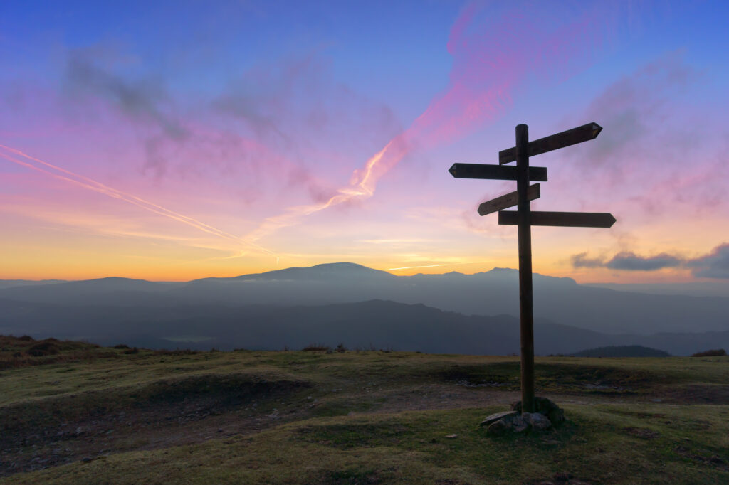 wooden signpost on mountain at sunset